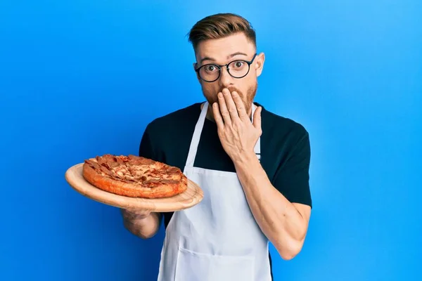 Fiatal Vörös Hajú Férfi Pincér Kötényt Visel Kezében Pizza Borító — Stock Fotó