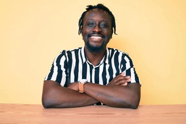 Saçları Örgülü Masaya Oturmuş Kollarını Kavuşturup Kameraya Bakarken Gülümseyen Afro — Stok fotoğraf