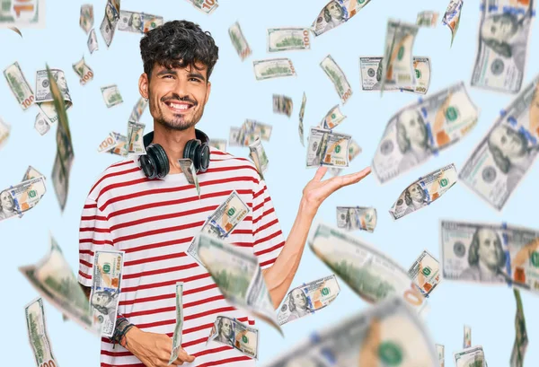 Genç İspanyol adam kulaklıkla müzik dinliyor. Neşeli bir şekilde gülümsüyor ve avuç içi kameraya bakıyor..