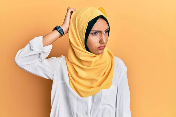 伝統的なイスラムのヒジャーブスカーフを身に着けている若いブルネットのアラブ女性は混乱し 質問について疑問に思う 疑いもなく頭に手を置いて考える 包括的な概念は — ストック写真
