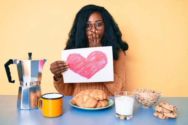 美しいアフリカの女性が手で口をカバー朝食を持って心臓の形の紙を保持し ショックを受け 間違いを恐れている 驚きの表情 — ストック写真