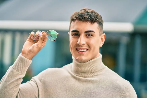 Joven Hombre Hispano Sonriendo Feliz Sosteniendo Gafas Ciudad — Foto de Stock