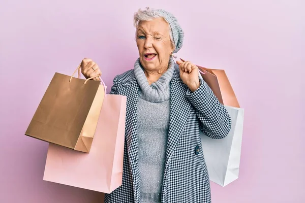 Senior Mulher Cabelos Grisalhos Segurando Sacos Compras Piscando Olhando Para — Fotografia de Stock