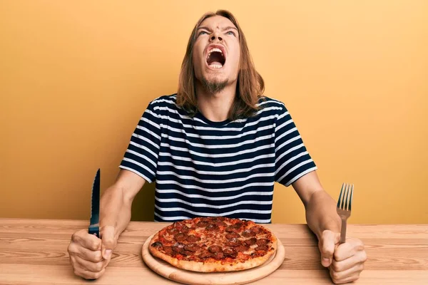 Jóképű Fehér Férfi Hosszú Hajjal Finom Pepperónis Pizzát Eszik Dühös — Stock Fotó