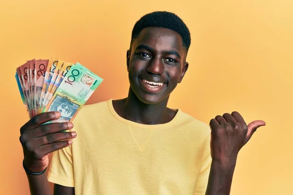 Молодий Афроамериканець Який Тримає Астраліанські Долари Вказуючи Пальцем Бік Посміхаючись — стокове фото