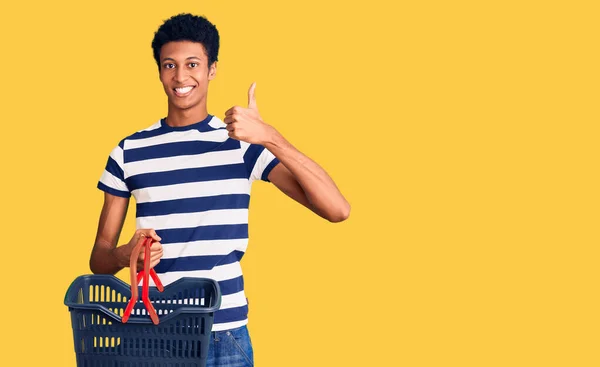 年轻的非洲裔美国人拿着超市购物篮 开心而积极地微笑着 竖起大拇指做得很出色 签了字 — 图库照片