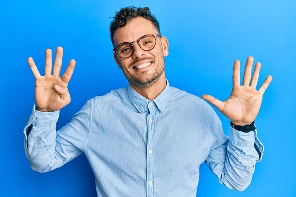 自信と幸せ笑顔ながらカジュアルな服や眼鏡を身に着けている若いヒスパニック系の男は 指の番号9で表示し 指摘します — ストック写真