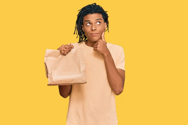 Ung Afrikansk Amerikansk Man Håller Bort Papperspåse Allvarligt Ansikte Tänker — Stockfoto