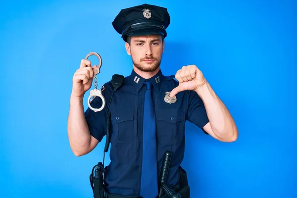 Mladý Běloch Policejní Uniformě Držící Pouta Rozzlobeným Obličejem Negativní Znamení — Stock fotografie