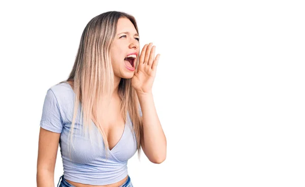 若い美しいブロンドの女性はカジュアルな服を着て大声で叫び 口の中で手で横に大声で叫ぶ コミュニケーションの概念 — ストック写真