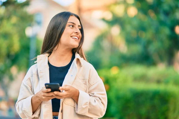 Νεαρή Ισπανόφωνη Κοπέλα Χαμογελά Ευτυχισμένη Χρησιμοποιώντας Smartphone Στο Πάρκο — Φωτογραφία Αρχείου
