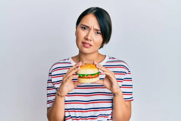 Beautiful Young Woman Short Hair Eating Hamburger Clueless Confused Expression — Stock Photo, Image