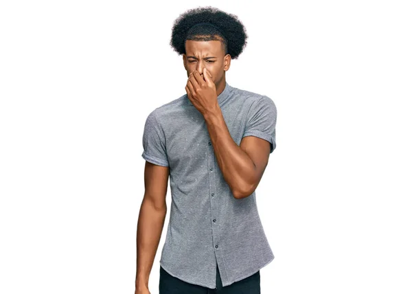 アフリカ系アメリカ人の男性は カジュアルな服を着て 臭いと嫌な 耐え難い匂いを嗅ぎ 鼻の上に指で息を保持します 臭いが悪い — ストック写真