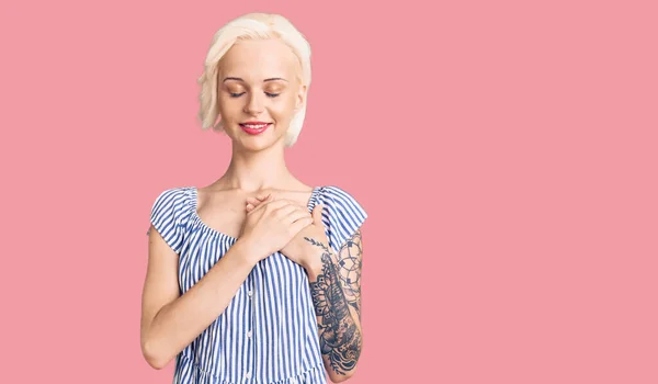 Mladá Blondýnka Tetováním Neformálním Oblečení Usmívající Rukama Hrudi Zavřenýma Očima — Stock fotografie