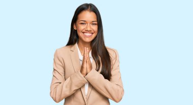 Güzel İspanyol kadın, iş ceketi giyiyor, elleriyle dua ediyor, af diliyor, kendinden emin bir şekilde gülümsüyor.. 