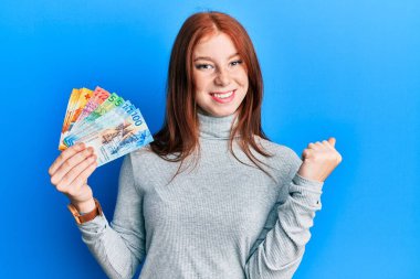 Elinde İsviçre frangı banknotları tutan genç kızıl saçlı kız gururla haykırıyor, zaferi ve başarıyı kutluyor. 