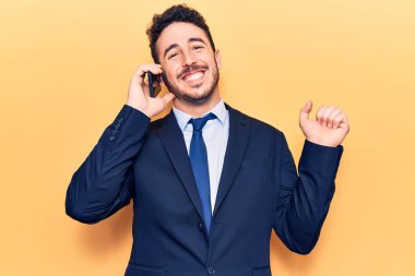 Takım elbiseli genç İspanyol adam akıllı telefonda konuşuyor gururla bağırıyor, zaferi kutluyor ve kollarını kaldırarak çok heyecanlı bir şekilde başarıya ulaşıyorlar. 