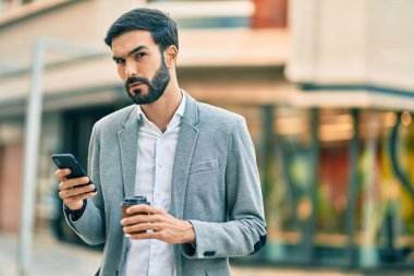 Zeki telefon kullanan ve şehirde kahve içen Latin asıllı genç bir işadamı..