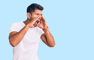 Gündelik kıyafetler giyen genç latin adam elleri ağızda bağırarak bağırıyor. 