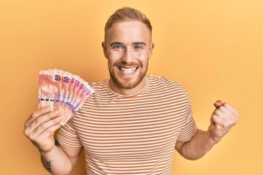 Güney Afrika 'nın 50 rand banknotunu elinde tutan genç beyaz adam gururla bağırıyor, zaferi ve başarıyı kutluyor. 