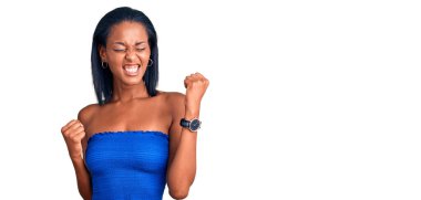 Genç Afro-Amerikan kadın günlük yaz kıyafetleri giyip kolları havada ve gözleri kapalı bir şekilde başarıyı kutluyor. Kazanan konsept. 