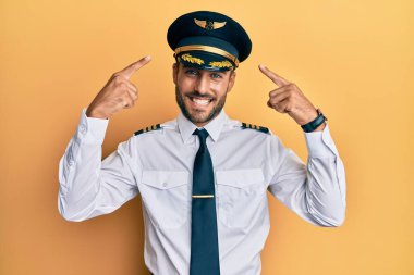 Yakışıklı, İspanyol üniformalı, pilot üniformalı, gülümseyen, iki eliyle başını gösteren, harika bir fikir ya da düşünce, iyi bir hafıza. 