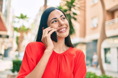 Genç Latin kız gülümsüyor. Şehirdeki akıllı telefondan konuşuyor..