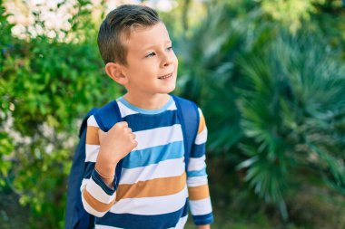 Kafkasyalı bir öğrenci parkta mutlu bir şekilde gülümsüyor..