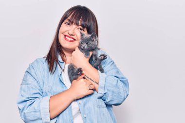 Genç, güzel, iri yarı, mutlu ve kendinden emin bir kadın. Yüzünde tebessümle durmuş, sevimli kediyi soyutlanmış beyaz arka planda tutuyor.