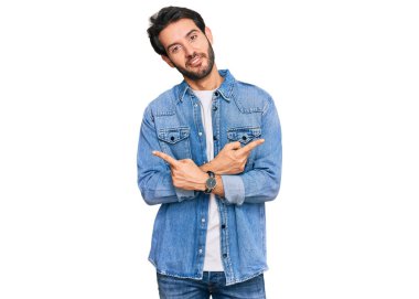 Gündelik kıyafetler giyen genç İspanyol adam her iki tarafı da parmaklarıyla işaret ediyor, farklı yönlerde farklı görüşler. 