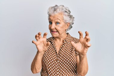 Yaşlı, gri saçlı, günlük kıyafetler giyen, korku ifadesinden korkan, dehşete düşmüş, elleriyle hareket etmeyi kesen, şok içinde bağıran bir kadın. panik konsepti. 