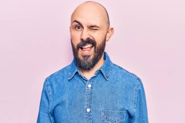 Gündelik kıyafetler giyen genç yakışıklı adam kameraya seksi bir ifadeyle bakıyor, neşeli ve mutlu bir yüzle.. 