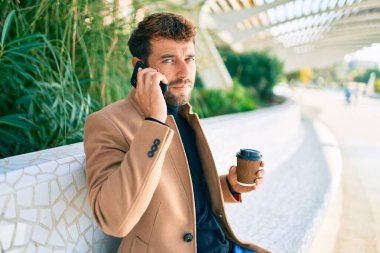 Zarif ceketli yakışıklı bir iş adamı. Açık havada akıllı telefon kullanıyor.