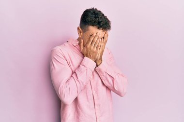 Ağlarken yüzünü ellerle kapatan, günlük kıyafetler giyen İspanyol genç adam. depresyon kavramı. 