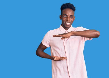 Genç Afrikalı Amerikalı sıradan kıyafetler giyen, elleri büyük ve büyük boy işareti gösteren, ölçü sembolü olan bir adam. Kameraya bakıp gülümsüyor. ölçüm kavramı. 