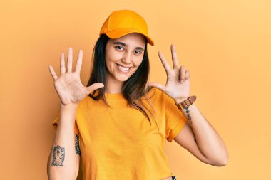 Dağıtım üniforması giyen, şapkalı genç İspanyol kadın sekiz numaralı parmaklarını göstererek gülümseyerek mutlu ve kendinden emin bir şekilde gülümsedi.. 