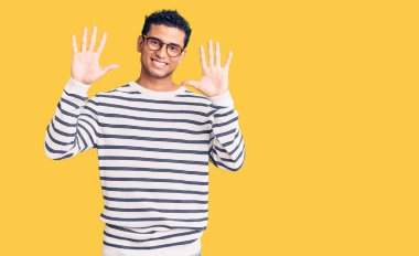 İspanyol asıllı yakışıklı genç adam gündelik giysiler ve gözlük takıyor ve parmaklarını on numaraya gösteriyor.. 