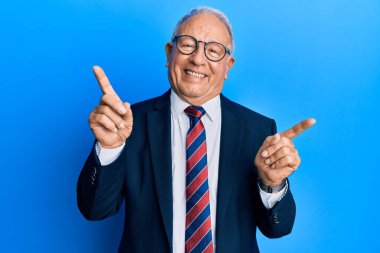 Takım elbiseli ve kravatlı kıdemli beyaz adam parmaklarıyla farklı yönleri işaret ederek gülümsüyor. reklam için kopyalama alanı 