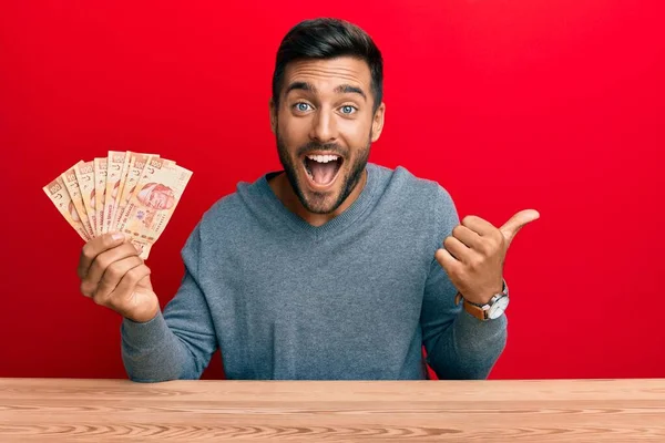 Hombre Hispano Guapo Sosteniendo Pesos Mexicanos Apuntando Con Pulgar Hacia —  Fotos de Stock