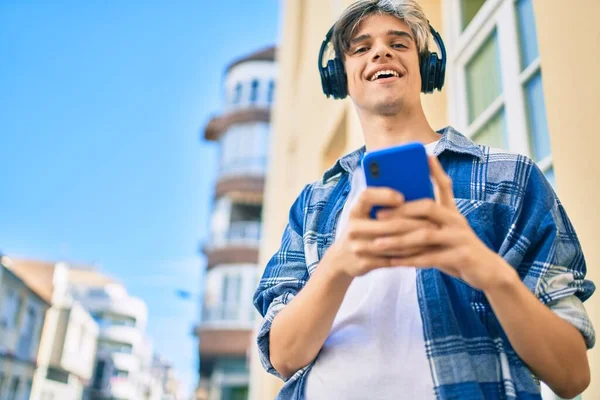 Νεαρός Ισπανόφωνος Χαμογελώντας Χαρούμενος Χρησιμοποιώντας Smartphone Και Ακουστικά Στην Πόλη — Φωτογραφία Αρχείου