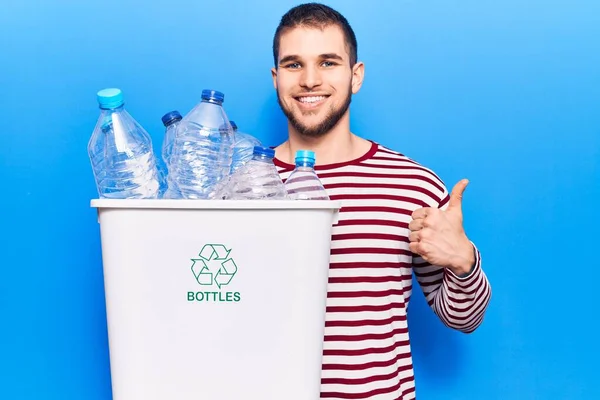若いですハンサムな男リサイクルプラスチックボトル笑顔と正 親指アップ行う優れた承認サイン — ストック写真