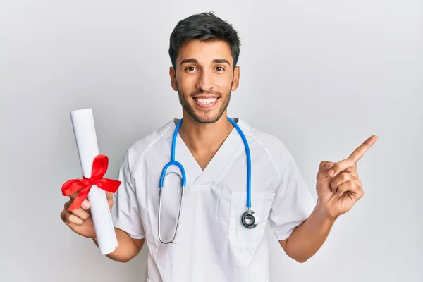 Joven Hombre Guapo Vistiendo Uniforme Médico Sosteniendo Grado Médico Sonriendo — Foto de Stock