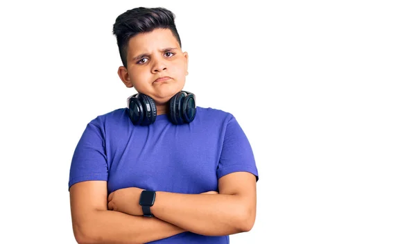 ヘッドフォンを装着した音楽を聞いている小さな男の子は懐疑的で緊張しており 顔に交差した腕で表現を否定しています 否定的な人 — ストック写真