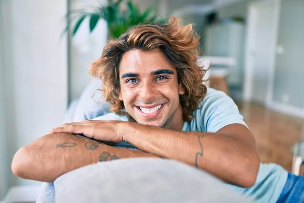 Joven Hombre Hispano Sonriendo Feliz Sentado Sofá Casa —  Fotos de Stock