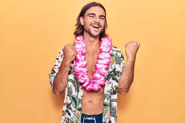 水泳ウェアを身に着けている若いハンサムな男とハワイのレイは誇りに思って叫んで 勝利と成功を祝う非常に興奮して腕を上げ — ストック写真