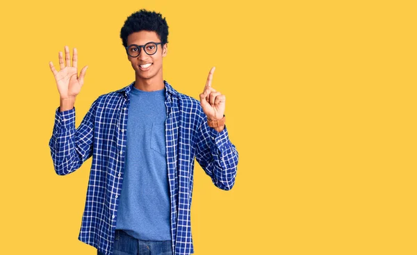 自信を持って幸せな笑みを浮かべている間 若いアフリカ系アメリカ人の男性は カジュアルな服や眼鏡を着て指の数6で示すと指摘します — ストック写真