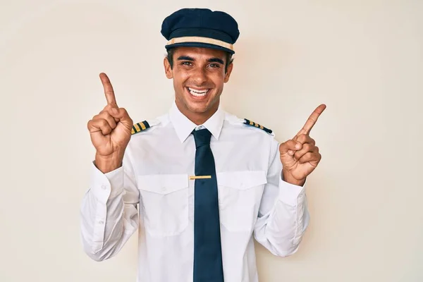 Junger Hispanischer Mann Flugzeugpilotenuniform Lächelt Selbstbewusst Und Zeigt Mit Den — Stockfoto