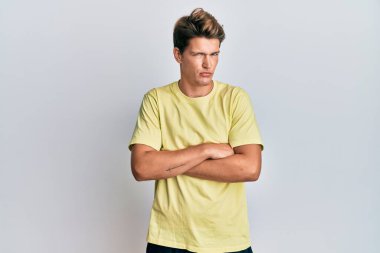 Gündelik kıyafetler giyen yakışıklı beyaz adam şüpheci ve gergin, yüzünde çapraz kollu tasvip etmeyen ifade. negatif kişi. 