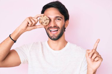 Yakışıklı İspanyol bir adam elinde kurabiyeyle mutlu bir şekilde gülümsüyor. 