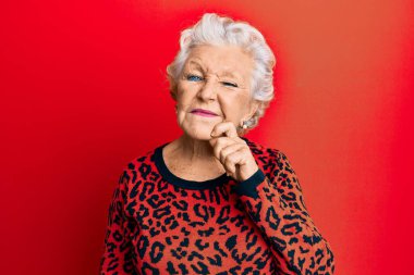 Kıdemli, gri saçlı, günlük kıyafetler giyen, şüpheyi düşünen, çenesinde parmak olan ve kafasını kaldırıp merak eden bir kadın. 